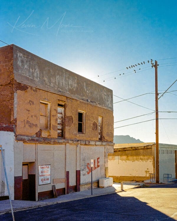 Decaying two-story building for sale in Superior, Arizona under a clear sky.