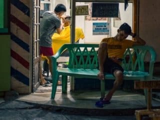 Nighttime Haircut at a Manila Intramuros Philippines Barbershop Barber giving haircut in busy nighttime barbershop scene.