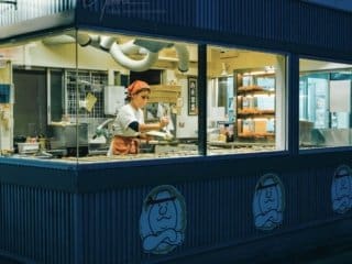 Evening bakery scene showing employee preparing Taiyaki (鯛焼き).
