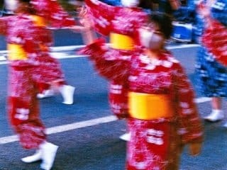 Japanese festival dancers in vibrant yukatas performing synchronized dance in urban setting.