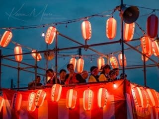 Vibrant Japanese festival with colorful lanterns and joyful crowd at dusk.