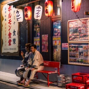 Couple relaxing at traditional Izakaya on a quiet Japanese street at night