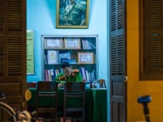 Late-night work Vietnamese Police Desk with portrait and motor scooter in sight.