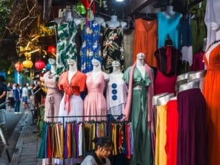 Colorful traditional dresses on mannequins in vibrant night market scene.