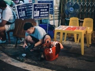 Night street scene with man cleaning shoes in urban Hanoi Vietnam
