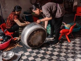 Kitchen Life: Traditional Vietnamese Food Preparation Two people preparing food in a rustic, traditional kitchen.