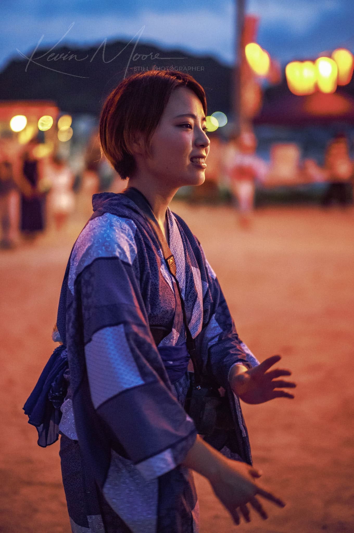 Young woman in blue yukata enjoying a lively Japanese summer festival evening.