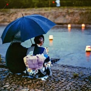 Japanese aesthetic art: a couple in yukata watch floating lanterns at the Toro Nagashi lantern festival in Iwaki, Japan