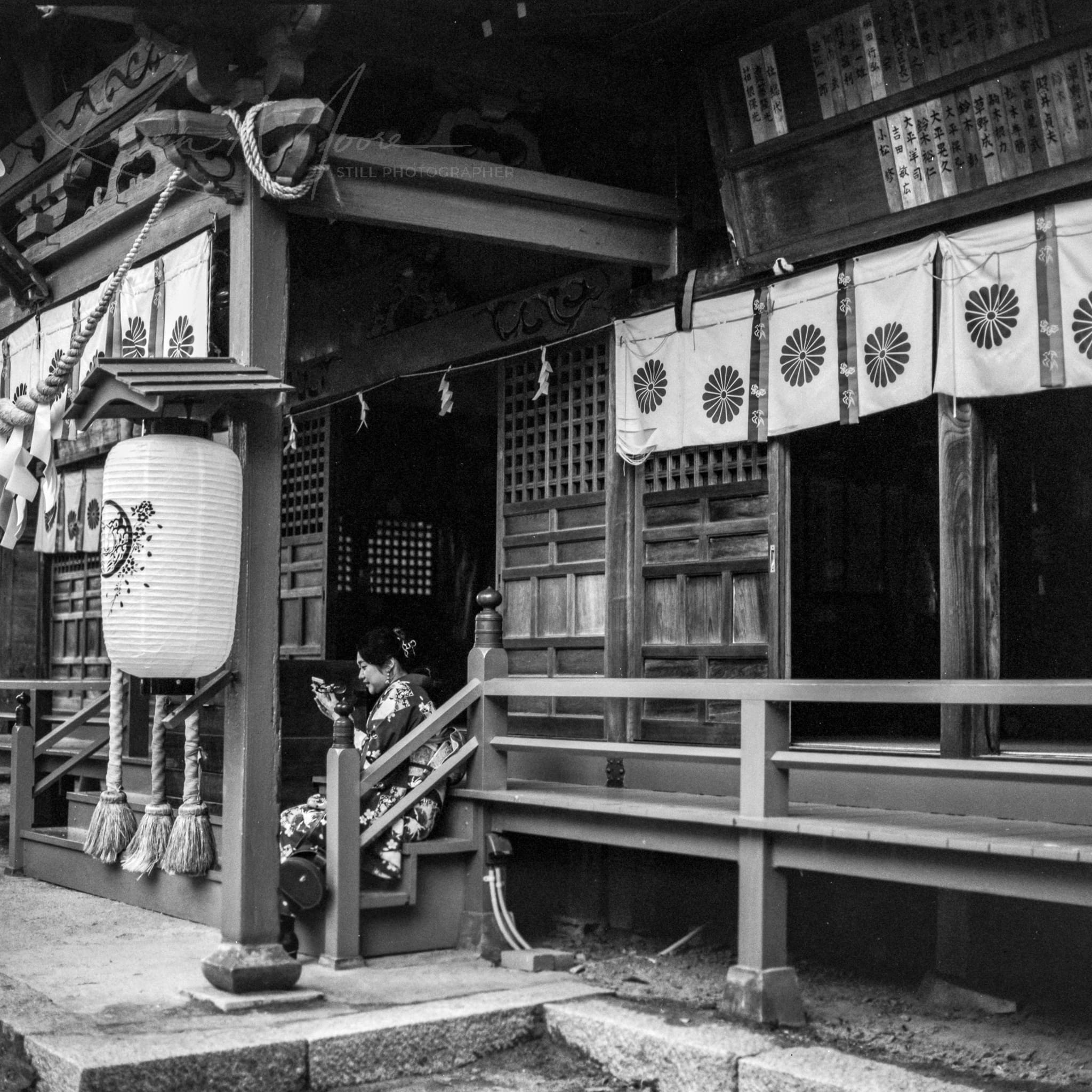 Black and white photo of a woman at a serene traditional Japanese shrine.