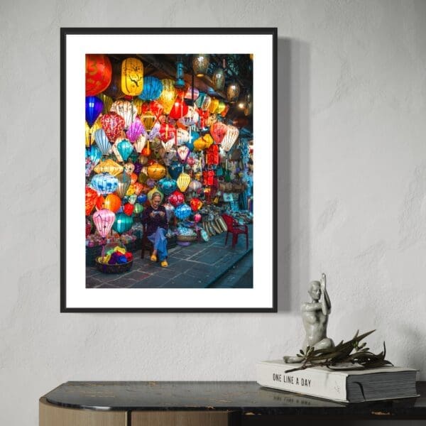 Framed photo of vibrant lantern market above modern console table with artistic and literary decor.