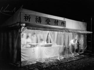 Moonlit Market: Bustling Night Scene in Urban China Night market in Chinese urban area with tent and bustling figures captured in black and white.