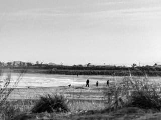 Serene Beach Day: Family, Reflections, and Nostalgic Charm Timeless black and white beach scene with family and reflective sand.