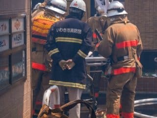 Japanese firefighters in action, wearing protective gear and assessing the situation.
