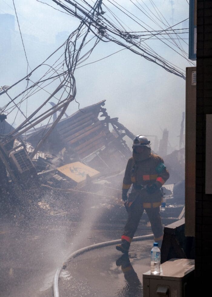 Firefighter navigates through smoke and debris of a collapsed building in disaster response.