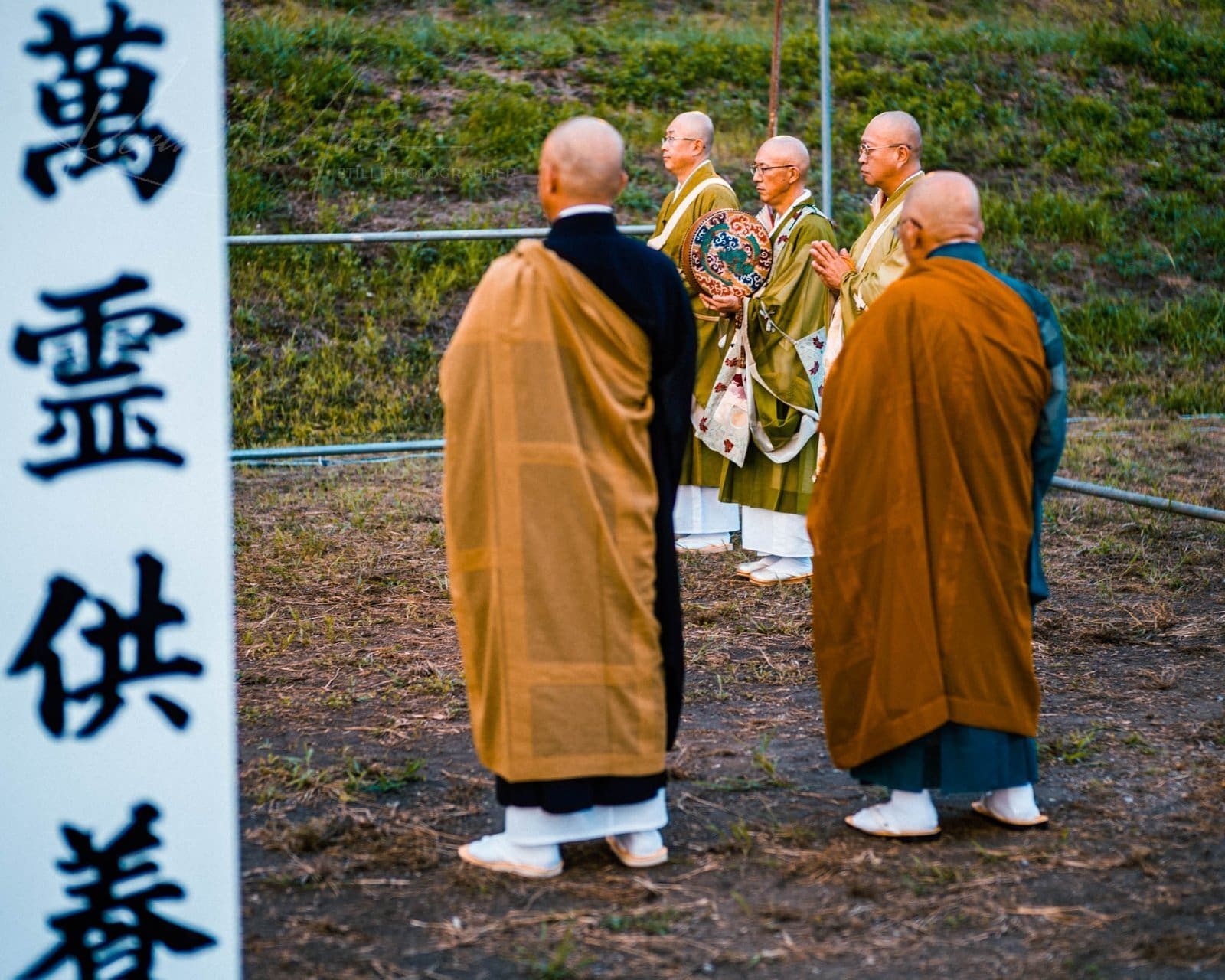 Group of Buddhist monks in traditional robes during an outdoor ceremony.