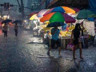 Rain-soaked Philippines urban market scene with colorful umbrellas and bustling crowd.