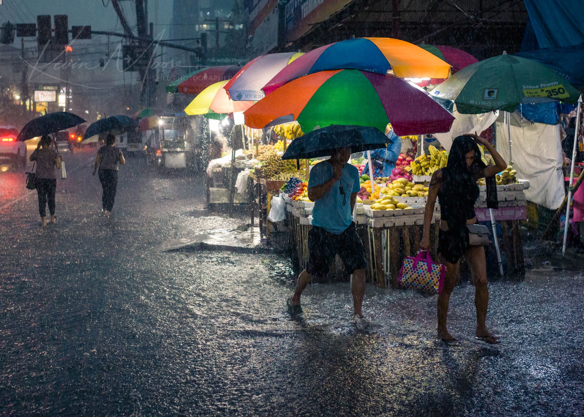 Rain-soaked Philippines urban market scene with colorful umbrellas and bustling crowd.