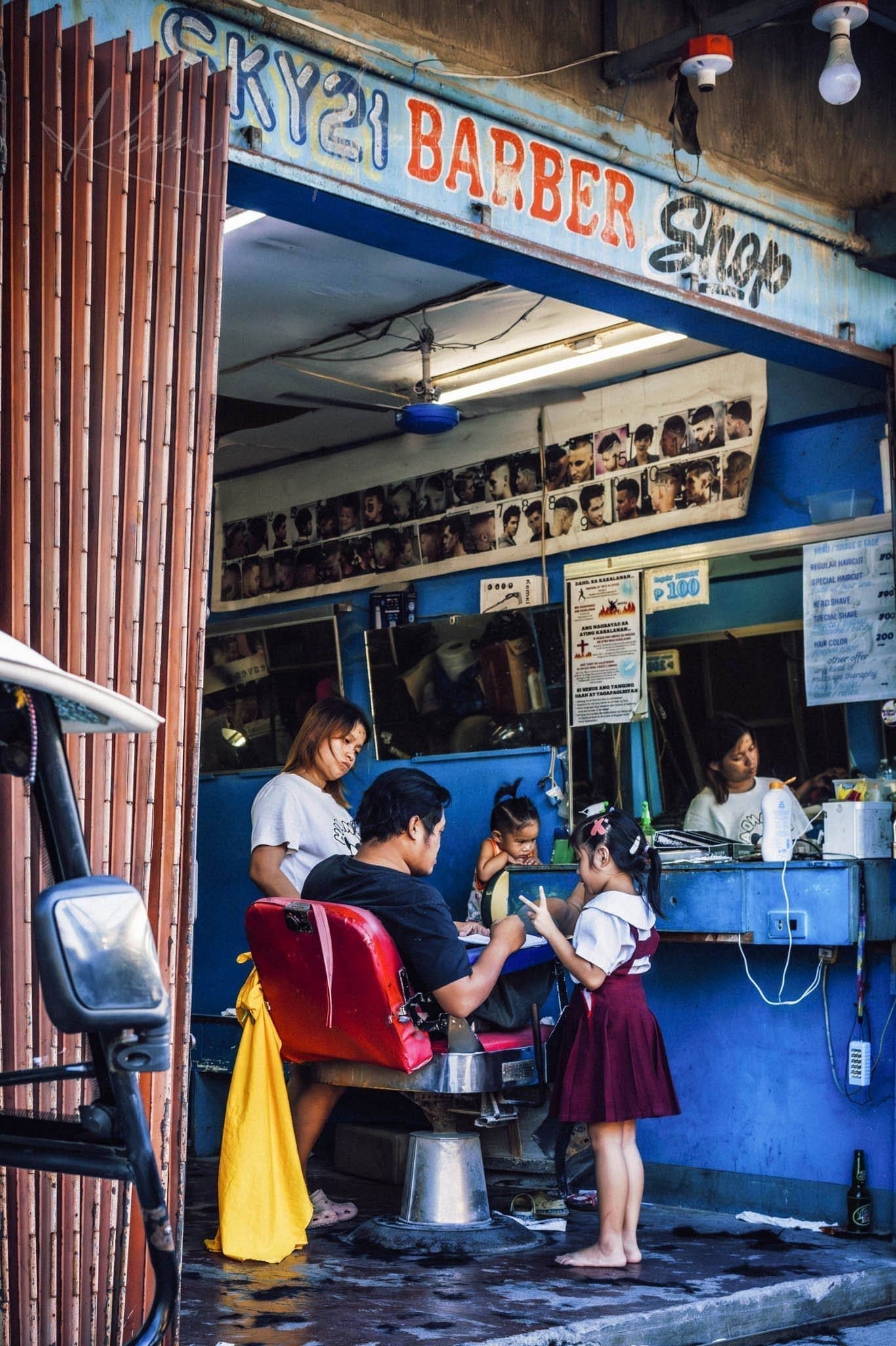 Barber attentively cuts hair of child in vibrant Philippines barber shop.