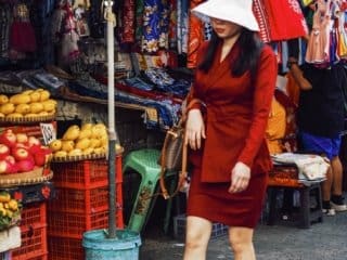 Woman in red dress shops at vibrant Philippine market.