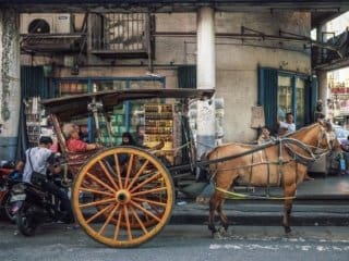 Charming Calesa Carriage Amidst Modern City Life Traditional calesa carriage in bustling city street with modern and historic elements.
