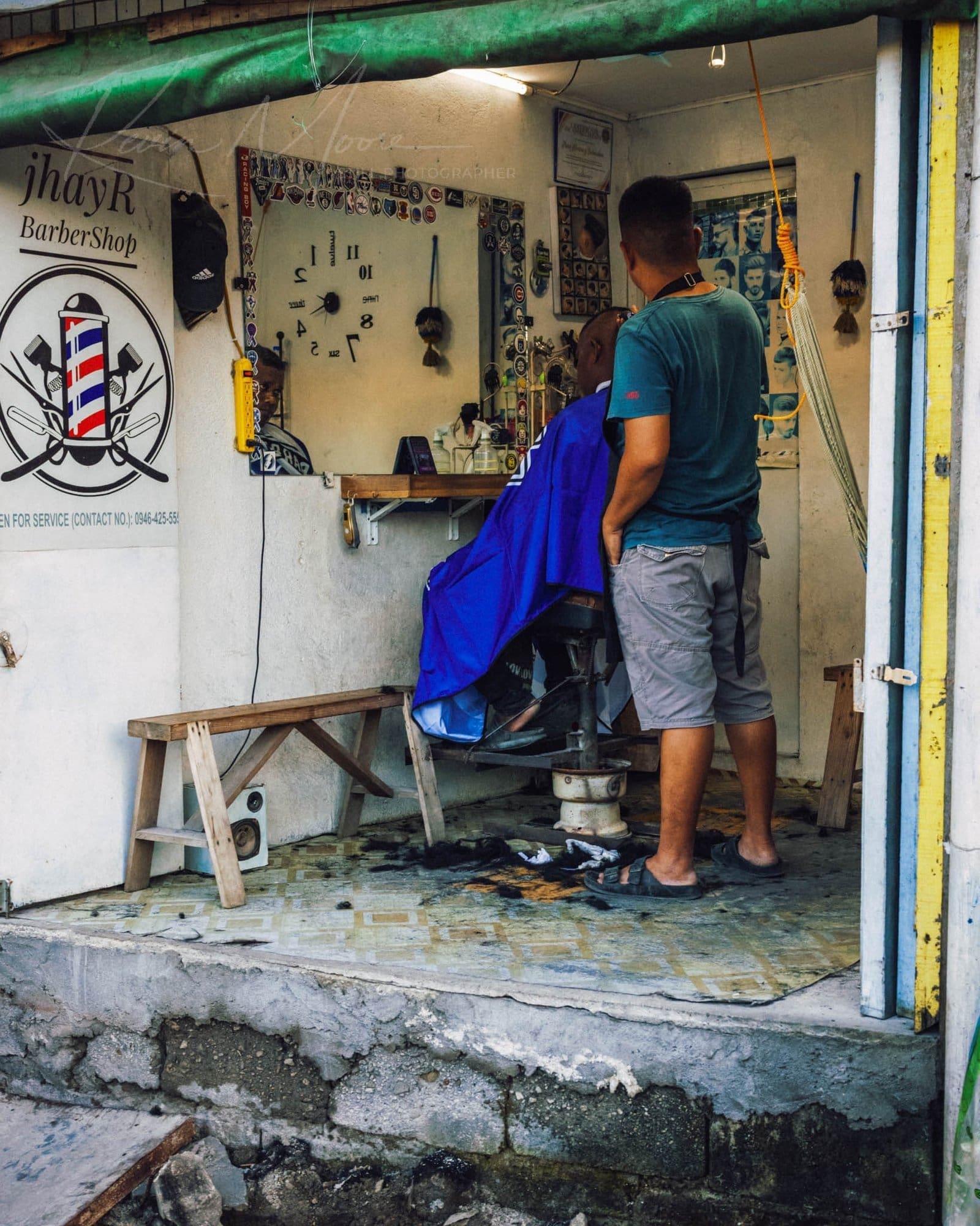 Barber cutting hair in a bustling urban Philippines barbershop scene.