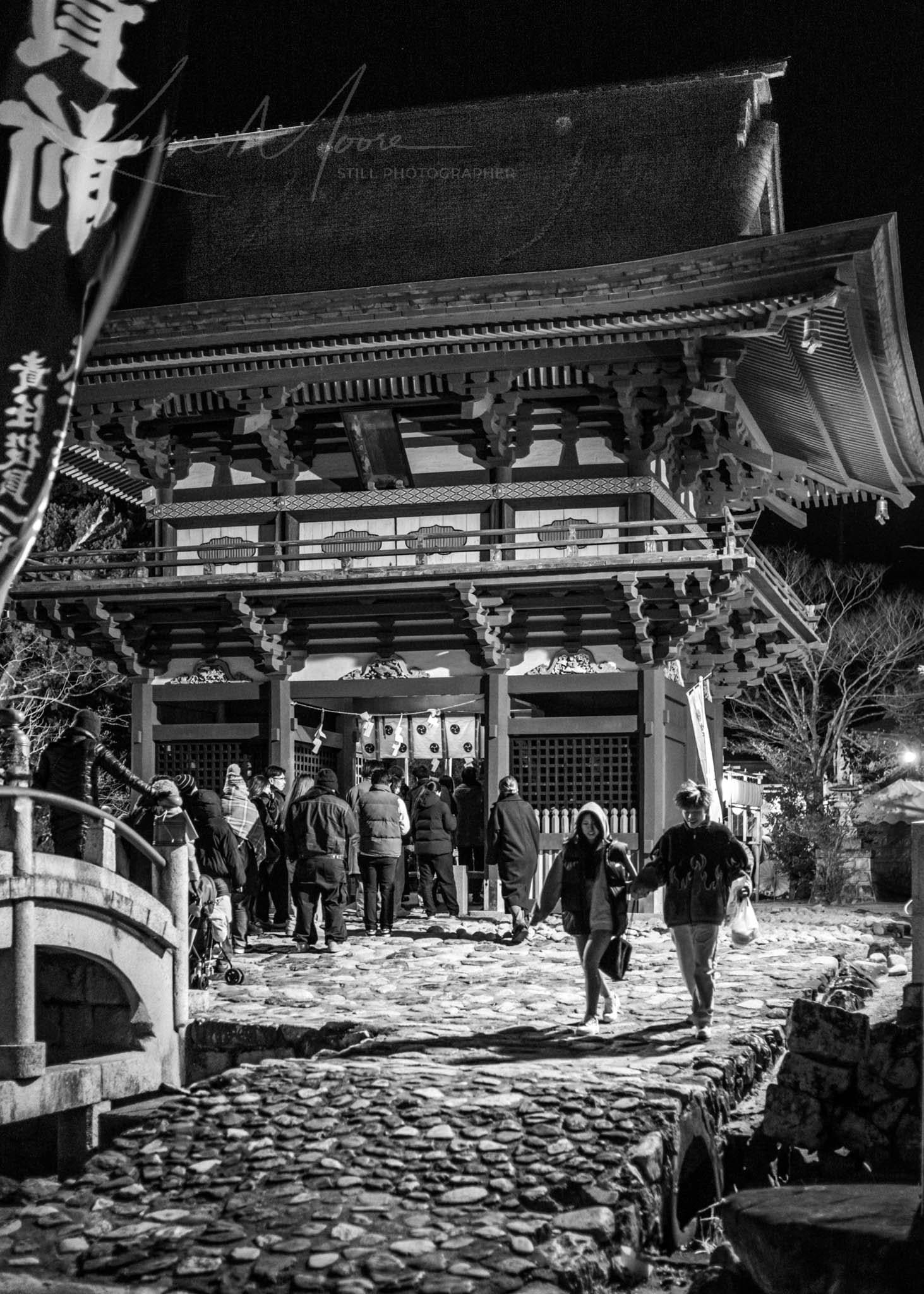 Night Photography Japan showcasing a serene Japanese shrine illuminated by lanterns under the moonlight.