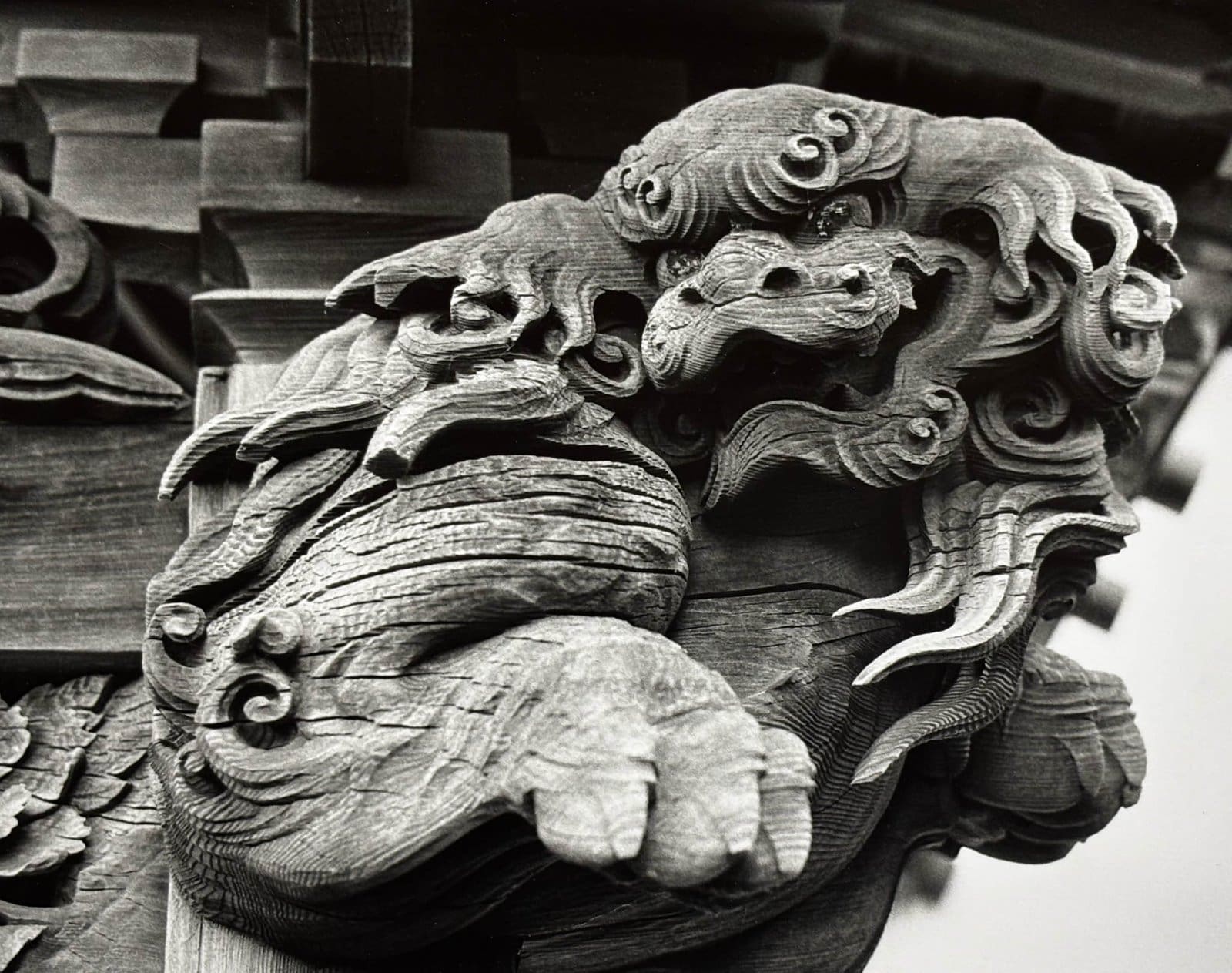 Black and white close-up of a Japanese temple carving — ornate wooden shishi guardian at Akaidake Temple, Fukushima