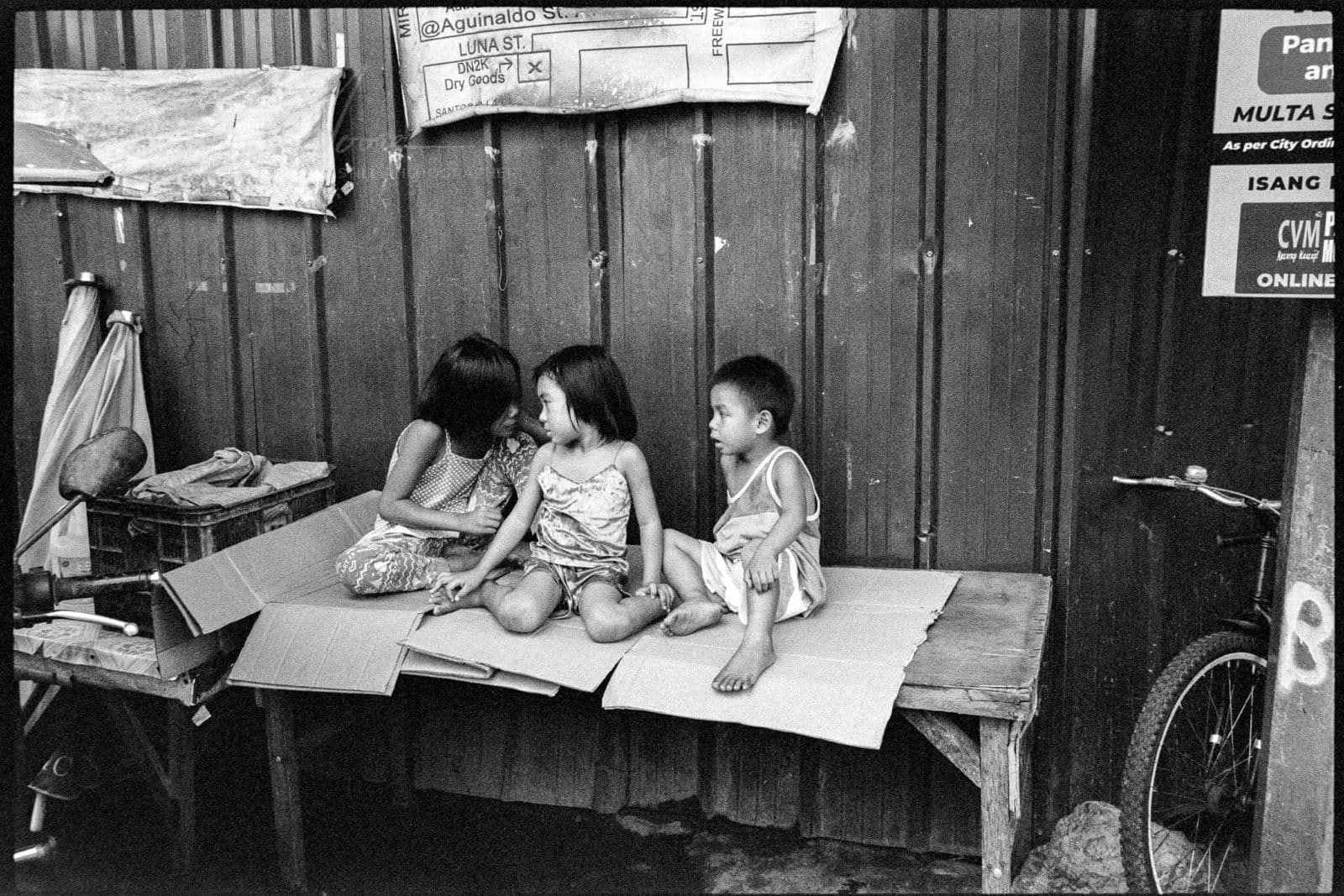 Candid portrait print — two siblings sharing a quiet moment at an urban market in Angeles City, Philippines.
