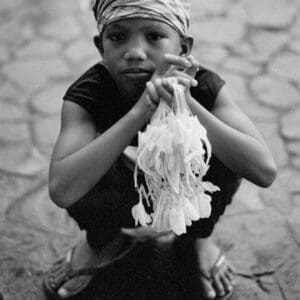 Filipino boy portrait — a young sampaguita flower vendor with a direct gaze outside a church in Pampanga.