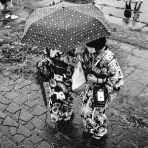 Two women in yukata sharing an umbrella in the rain, a black and white Japanese rain print from Iwaki, Japan